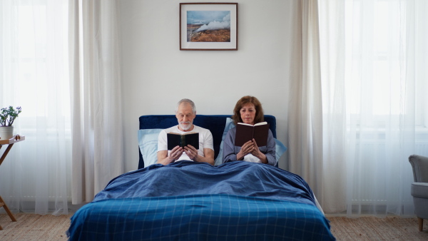 Senior couple in bed, reading books in the morning.