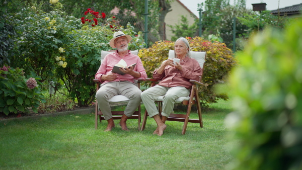 Elderly couple sitting in garden chairs, resting, talking to each other.