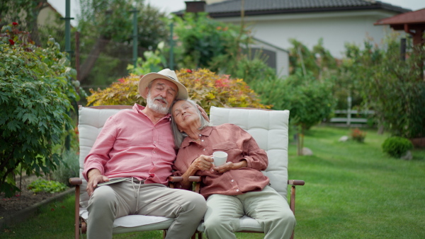 Senior couple sitting in garden, relaxing, embracing.