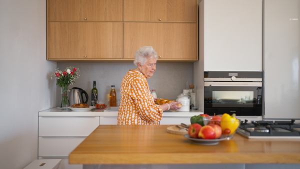 Happy senior woman serving a homemade sweet braided bread with raisins.