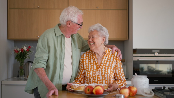 Happy senior couple holding homemade sweet braided bread with raisins.