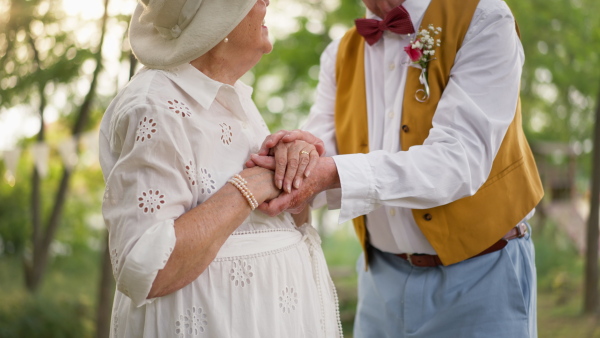 A mid section of senior hands with wedding rings during their marriage.