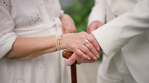 A mid section of senior hands with wedding rings during their marriage.