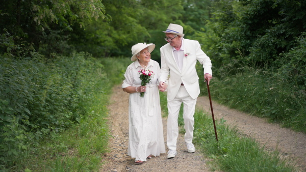 Happy senior couple having marriage, walking in forest, during a summer day.