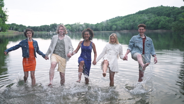 a Multiracial group of young friends splashing in lake in summer.