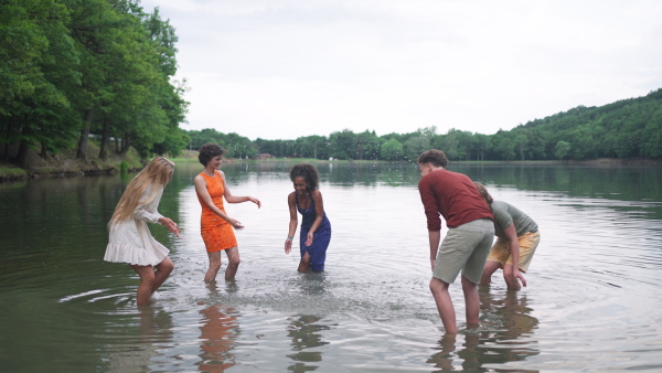 a Multiracial group of young friends splashing in lake in summer.