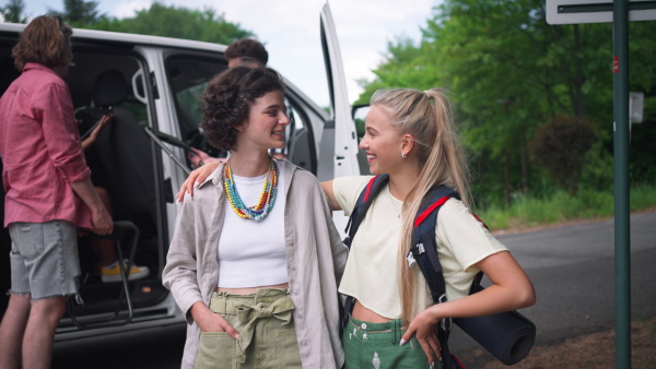 A multiracial young friends travelling together by car, standing by car and talking - summer vacation, holidays, travel, road trip and people concept.