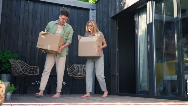 A cheerful young couple celebrating moving in their new tiny house in woods. Conception of moving and sustainable living.