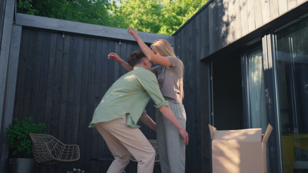 A cheerful young couple celebrating moving in their new tiny house in woods. Conception of moving and sustainable living.