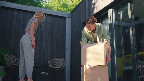 A cheerful young couple celebrating moving in their new tiny house in woods. Conception of moving and sustainable living.