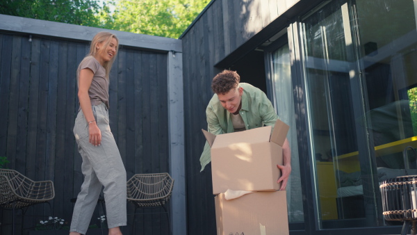 A cheerful young couple celebrating moving in their new tiny house in woods. Conception of moving and sustainable living.