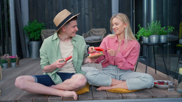 A cheerful young couple in love eating slice of watermelon together