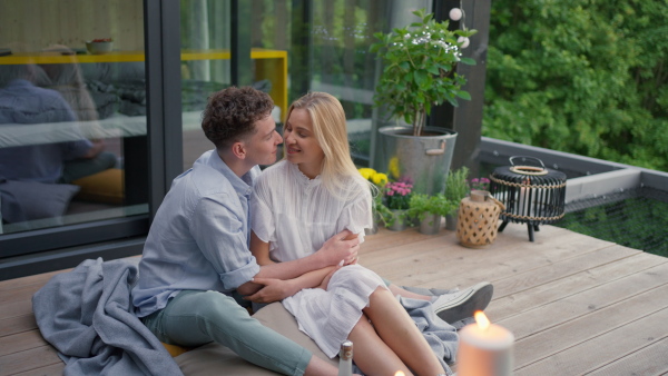 A young couple in love cuddling and kissing outdoors on terrace, weekend away in tiny house in countryside, sustainable living.