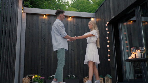 A young couple dancing outdoors, weekend away in tiny house in countryside, travel and holiday concept.