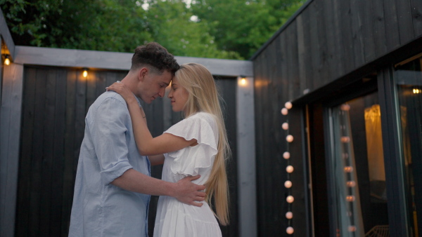 A young couple dancing outdoors, weekend away in tiny house in countryside, travel and holiday concept.