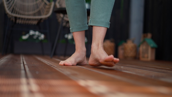 Close-up of male feet walking barefoot on wooden terrace.