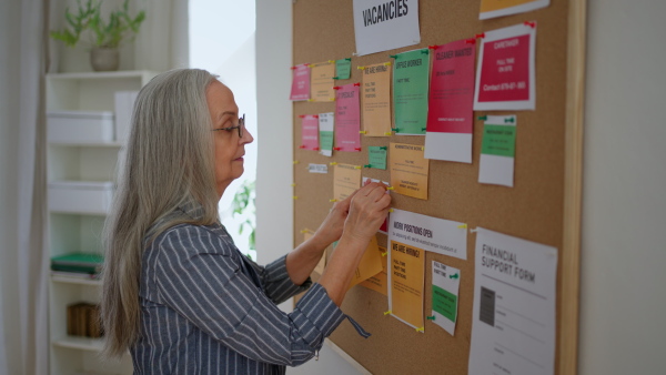 A job center employee pinning job vacancies on employment noticeboard.