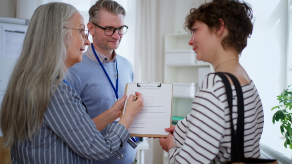 A job centre employee helping young woman to fill form to find a job.