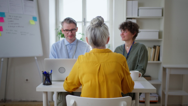 a Rear view of senior woman at job interview.