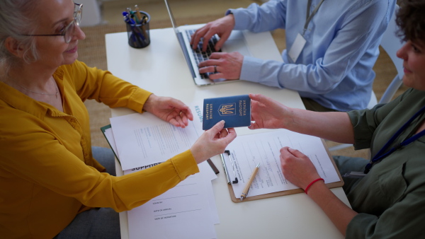 A woman and man volunteers helping Ukrainian woman to fill in forms at immigration office.