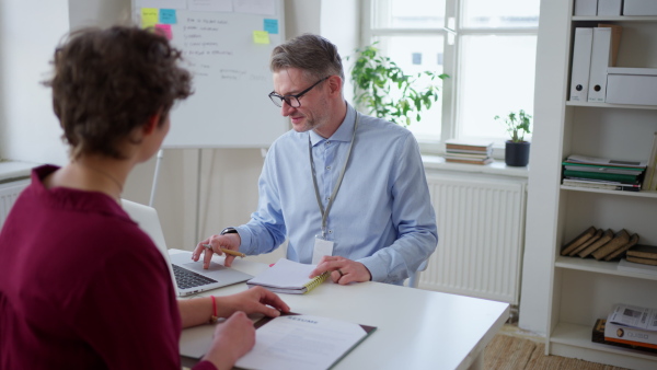 A mature mman recruiter smiling at young candidate during the job interview.