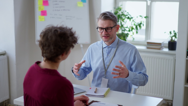 A mature mman recruiter smiling at young candidate during the job interview.