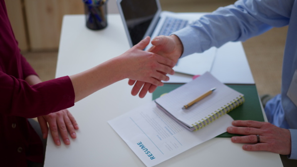 A man recruiter shaking hands with young candidate during the job interview.