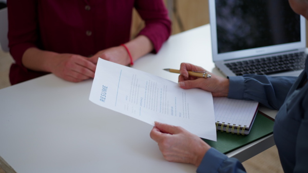 A senior woman recruiter holding papers during the job interview, close-up.