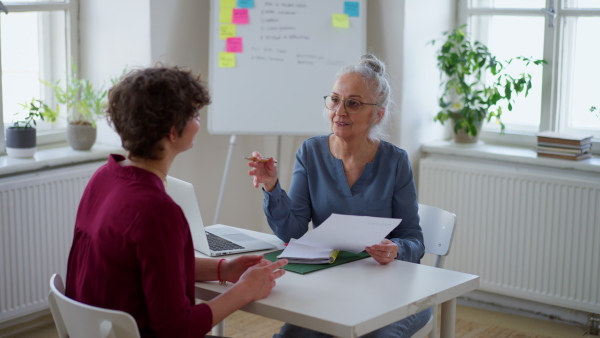 A senior woman recruiter holding papers and talking during the job interview.