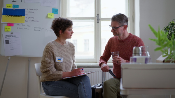 A young woman volunteer helping Ukrainian man to fill in forms at asylum centre.