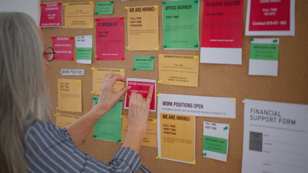 A job center employee pinning job vacancies on employment noticeboard.