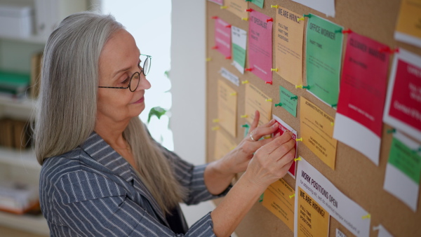 A job center employee pinning job vacancies on employment noticeboard.