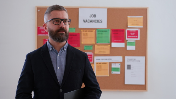 A job center employee standing in front of employment noticeboard.