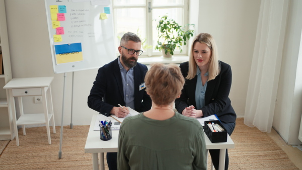 A woman and man volunteers helping Ukrainian woman to fill in forms at immigration office.