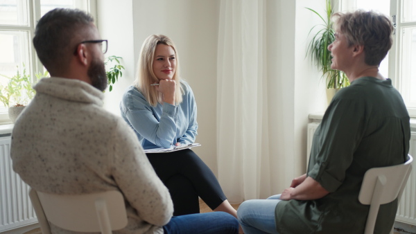 A therapist with people communicating while sitting in circle and talking, group therapy.