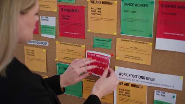 A job center employee pinning job vacancies on employment noticeboard.