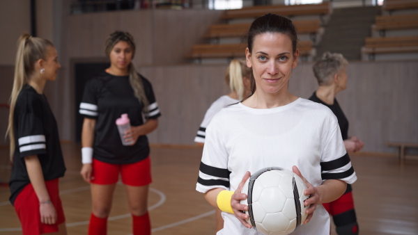 A young woman footabll player in gym looking at camera during training.