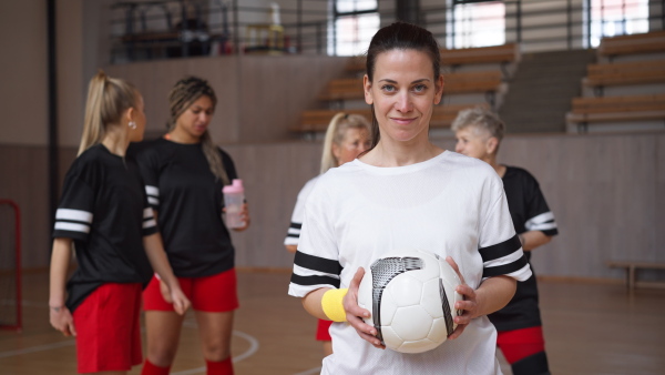 A young woman footabll player in gym looking at camera during training.