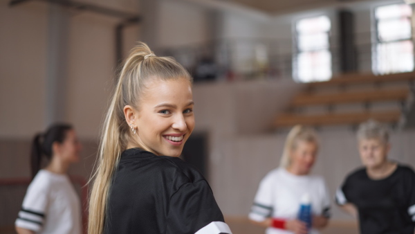 A young woman footabll player in gym looking at camera during training.