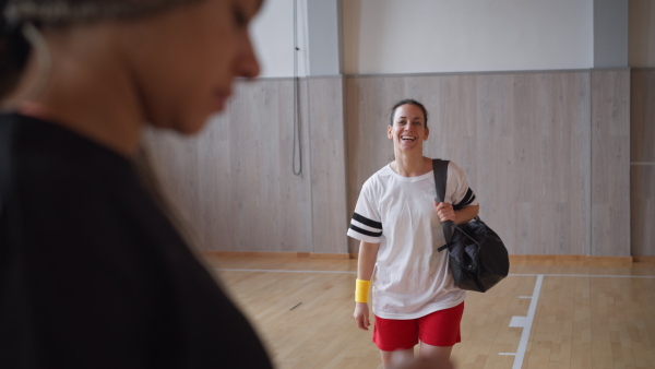 A young woman, sports player fist bumping and greeting with team players in gym.