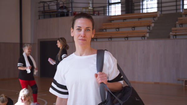 A young woman basketball player in gym looking at camera when coming for training.