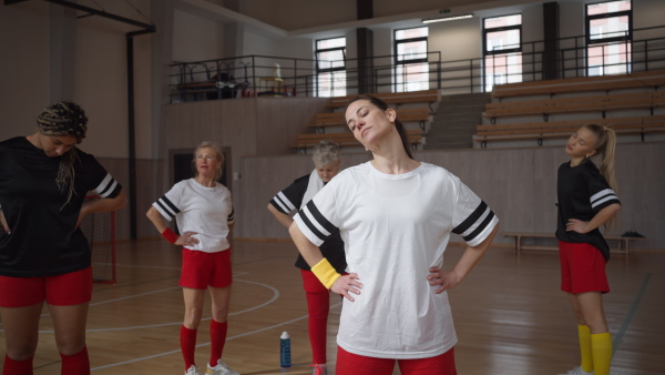 A group of young and old women, sports team players in gym, doing work out exercise.