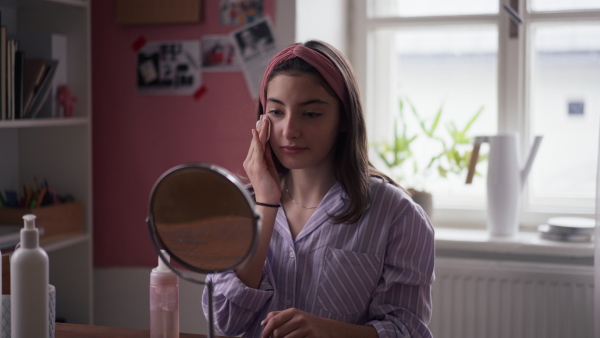 Teenage girl doing her skin care routine in the room.