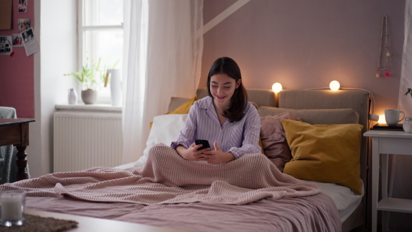 Young teenage girl srolling her smartphone in a room.