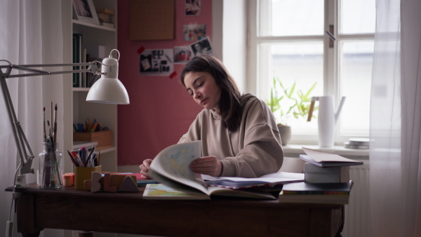 Young teenage girl studying and doing homework in her room, having a mental breakdown.