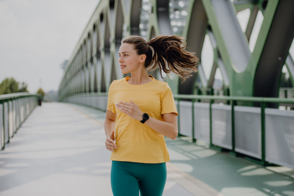 Young woman jogging at a city bridge, healthy lifestyle and sport concept.