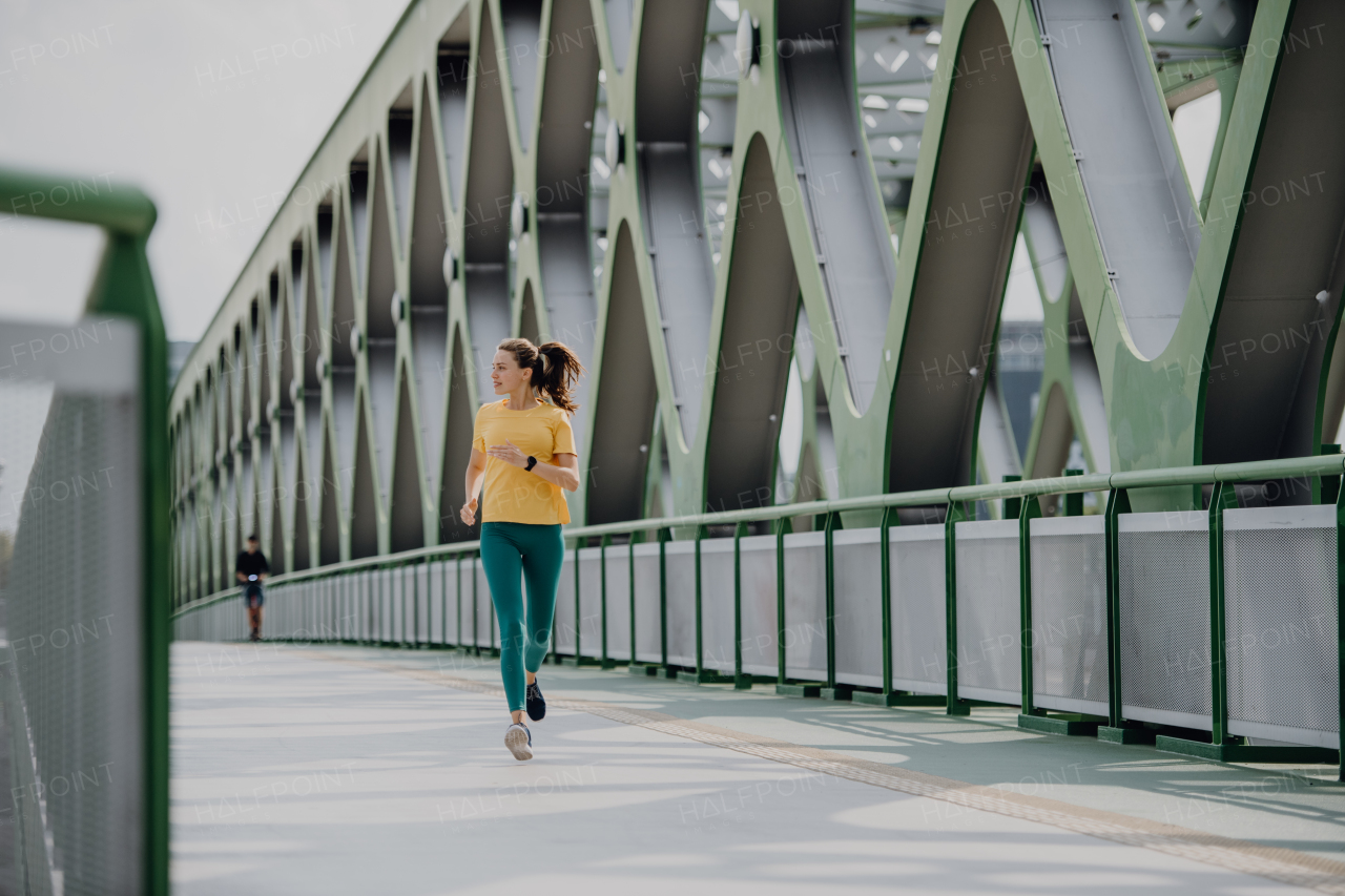 Young woman jogging at a city bridge, healthy lifestyle and sport concept.