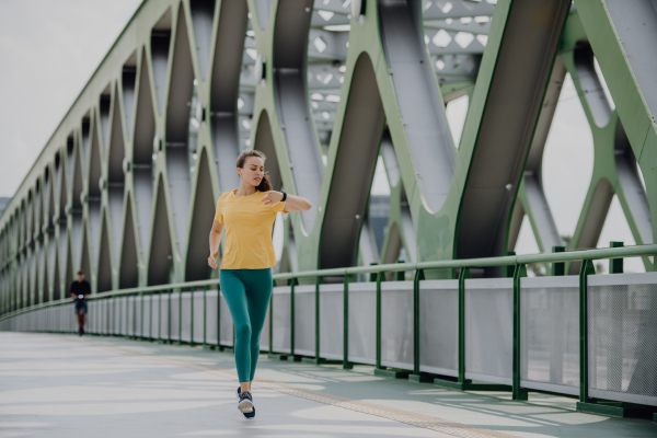 Young woman jogging at a city bridge, healthy lifestyle and sport concept.