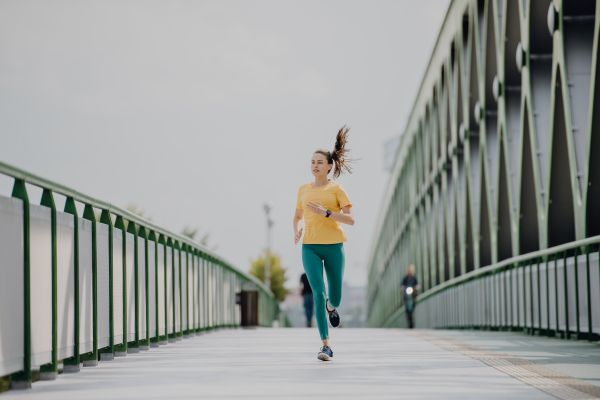 Young woman jogging at a city bridge, healthy lifestyle and sport concept.