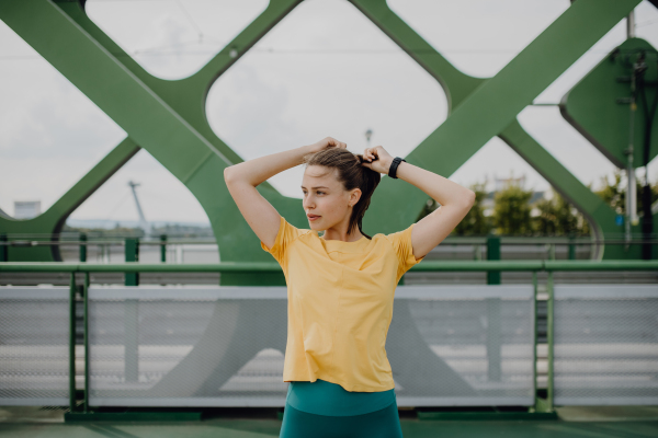 Portrait of young sportive woman resting outdoor in a city after running.